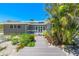 Inviting coastal home with a charming walkway leading to a covered front porch and lush tropical foliage at 8592 Hidden Lagoon Rd, Sarasota, FL 34242