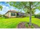 Beautifully landscaped backyard with mature trees, lush green grass, and a screened lanai at 8721 Trattoria Ter, Sarasota, FL 34238