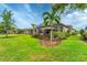 Expansive backyard with lush green grass, mature landscaping, and a screened lanai at 8721 Trattoria Ter, Sarasota, FL 34238