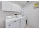 Bright laundry room features white appliances, tile flooring, and ample storage in overhead cabinets at 8824 Havenridge Dr, Sarasota, FL 34238