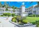 Exterior view of condo building with lush landscaping, colorful flowers, and palm trees against a blue sky at 9630 Club South Cir # 6209, Sarasota, FL 34238