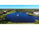 Aerial view of a tranquil pond with a water feature, surrounded by lush greenery and nearby homes at 9630 Club South Cir # 6209, Sarasota, FL 34238