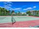 Enjoy a game on the community tennis court, surrounded by lush landscaping and fencing, under a sunny sky at 9630 Club South Cir # 6209, Sarasota, FL 34238
