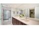 Bathroom featuring double sinks with white countertops and dark cabinets leading to shower and closet at 99 Sunset Dr # 102, Sarasota, FL 34236