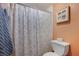 This bathroom features a shower with a decorative curtain, a toilet, and framed seashell art hung on the peach colored wall at 1110 49Th Avenue W Dr, Bradenton, FL 34207
