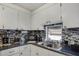Well-lit kitchen featuring white cabinets, a stylish backsplash, and a stainless steel sink at 1110 49Th Avenue W Dr, Bradenton, FL 34207