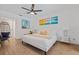 Tranquil bedroom with a white bed, modern ceiling fan, tropical artwork, and cozy chair at 11219 93Rd St, Largo, FL 33773