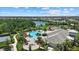 Aerial view of a community pool, clubhouse, playground and a lake surrounded by residences and palm trees on a sunny day at 12029 Cranston Way, Lakewood Ranch, FL 34211