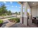 Inviting covered porch featuring brick flooring, sturdy support columns, and views of a landscaped street at 12029 Cranston Way, Lakewood Ranch, FL 34211
