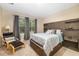 A modern bedroom with a stylish headboard, accent pillows, a cozy chair, and ample natural light from the windows at 12592 Ryegrass Loop, Parrish, FL 34219