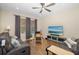 A cozy living room features a ceiling fan, a large TV, comfortable sofas, and natural light from a window at 12592 Ryegrass Loop, Parrish, FL 34219