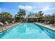 Community pool with ample lounge chairs and a cabana surrounded by lush greenery at 1322 Millbrook Cir, Bradenton, FL 34212
