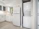 Modern white kitchen featuring updated appliances, a stacked washer/dryer, and ample counter space at 1421 57Th W St # 1421, Bradenton, FL 34209