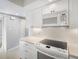 This kitchen features white cabinets, tile backsplash, quartz countertops, and modern appliances at 1421 57Th W St # 1421, Bradenton, FL 34209
