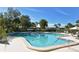 Large community pool surrounded by mature landscaping, tables, and chairs on a bright, sunny day at 1720 Glenhouse Dr # Gl430, Sarasota, FL 34231