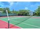 Community tennis court surrounded by a fence, trees, and landscaping on a sunny day at 1720 Glenhouse Dr # Gl430, Sarasota, FL 34231
