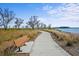 Concrete walking path with a wooden bench and natural landscaping with water view at 17549 Timberline Pkwy, Punta Gorda, FL 33982