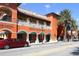 A view of Morton's Gourmet Market's exterior, featuring an orange facade with colonnades and palm trees at 1815 Grove St, Sarasota, FL 34239