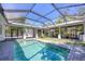 A beautiful backyard pool with a screened enclosure, lush landscaping, and an outdoor entertainment area at 1815 Grove St, Sarasota, FL 34239