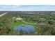 Aerial view of a modern home with a pond and a long driveway surrounded by lush greenery at 20307 74Th E Ave, Bradenton, FL 34202