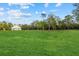 Backyard showcasing a well-maintained green lawn, mature trees, and a white outbuilding at 20307 74Th E Ave, Bradenton, FL 34202