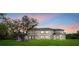 Expansive two-story modern home at sunset showcasing a lush green lawn and stately tree at 20307 74Th E Ave, Bradenton, FL 34202