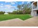 Expansive manicured lawn with scattered mature trees, concrete patio and a white outbuilding under a blue sky at 20307 74Th E Ave, Bradenton, FL 34202