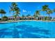 Expansive community pool with clear turquoise water, surrounded by palm trees and beautiful buildings at 227 Maraviya Blvd, Nokomis, FL 34275