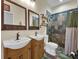 Well-lit bathroom showcasing dual sinks with mirrors, a tiled shower, and commode at 27207 Treadmill Dr, Punta Gorda, FL 33955