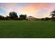 Expansive lawn leading to a home featuring a screened-in pool area and a view of the sunset sky at 3607 Twin Rivers Trl, Parrish, FL 34219