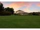 Expansive lawn with view of a home and screened pool area backed by the glow of a sunset sky at 3607 Twin Rivers Trl, Parrish, FL 34219