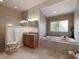 Elegant bathroom with a soaking tub, dual sinks, and tan tiling throughout the space at 3607 Twin Rivers Trl, Parrish, FL 34219