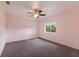 Sunny bedroom with a ceiling fan, neutral carpet, a big window, and soft, light-pink walls at 3607 Twin Rivers Trl, Parrish, FL 34219