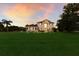 Charming two-story home with manicured lawn, portico entry and large windows, bathed in the glow of a sunset sky at 3607 Twin Rivers Trl, Parrish, FL 34219