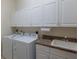 Well-equipped laundry room with white cabinets, washer, dryer, countertop, and a sink for added convenience at 3607 Twin Rivers Trl, Parrish, FL 34219
