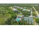 An aerial view shows a tennis court, pool, and several low-rise buildings in a wooded area at 5242 Manorwood Dr Dr # 3A, Sarasota, FL 34235