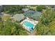 Aerial view of tennis courts, a swimming pool and hot tub, near a clubhouse, surrounded by lush trees at 5242 Manorwood Dr Dr # 3A, Sarasota, FL 34235