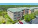 Corner view of a multi-story condo building featuring outdoor balconies, mature trees, and a well-maintained parking area at 5242 Manorwood Dr Dr # 3A, Sarasota, FL 34235