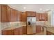 Modern kitchen featuring stainless steel refrigerator, granite counters, and wood cabinetry at 5242 Manorwood Dr Dr # 3A, Sarasota, FL 34235