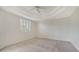 Cozy main bedroom featuring a tray ceiling, neutral carpeting, and plantation shutters at 5242 Manorwood Dr Dr # 3A, Sarasota, FL 34235