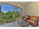 Enjoy this relaxing balcony with wicker furniture, a glass table, and peaceful green scenery at 5601 Bentgrass Dr # 10-105, Sarasota, FL 34235