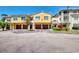 Two-story townhome featuring individual garages, sunny yellow paint, and well-manicured landscaping at 5601 Bentgrass Dr # 10-105, Sarasota, FL 34235