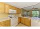 Cozy kitchen with white appliances, wood cabinets, and open floor plan view to the living room and balcony at 5601 Bentgrass Dr # 10-105, Sarasota, FL 34235
