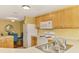 Bright kitchen featuring white appliances, wood cabinetry, and an adjacent dining area with blue chairs at 5601 Bentgrass Dr # 10-105, Sarasota, FL 34235