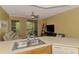 Open kitchen with stainless steel sink and white appliances, with view to the living room and balcony at 5601 Bentgrass Dr # 10-105, Sarasota, FL 34235