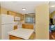 Bright kitchen featuring white appliances and light wood cabinetry with a view to the living area at 5601 Bentgrass Dr # 10-105, Sarasota, FL 34235