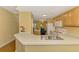 Open kitchen with light wood cabinetry, bar seating, adjacent to dining area, and view to the living area at 5601 Bentgrass Dr # 10-105, Sarasota, FL 34235