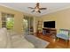 Bright living room with sliding glass doors to balcony, ceiling fan, and a comfortable white couch at 5601 Bentgrass Dr # 10-105, Sarasota, FL 34235