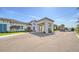 Elegant clubhouse entrance featuring a porte-cochere, lush landscaping, and well-maintained grounds at 5793 Long Shore Loop, Sarasota, FL 34238