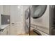 Modern laundry room featuring stacked washer and dryer, white cabinets, counter and herringbone backsplash at 5793 Long Shore Loop, Sarasota, FL 34238